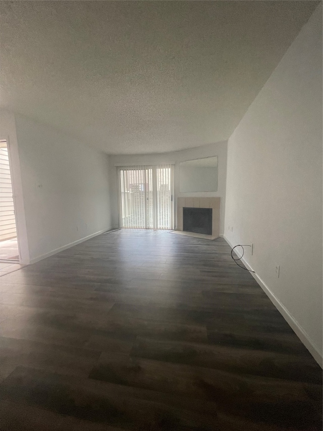 unfurnished living room with a textured ceiling, dark wood-type flooring, and a tile fireplace