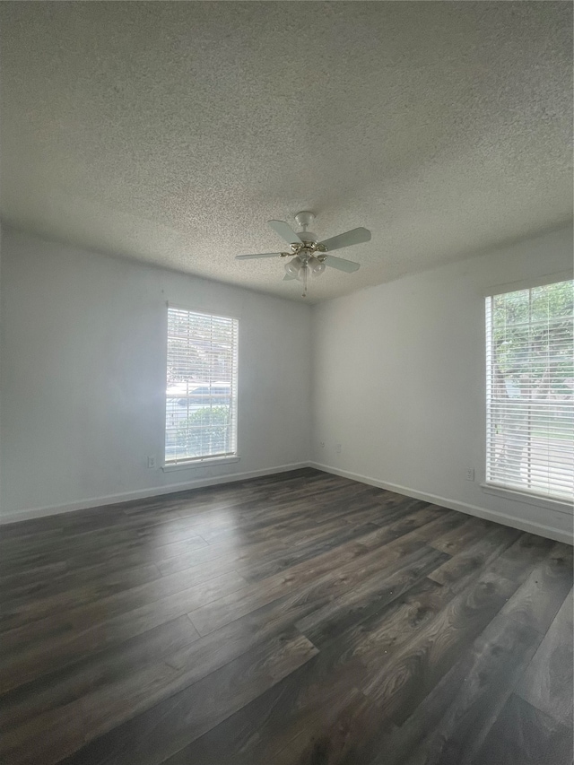 spare room featuring a wealth of natural light, dark hardwood / wood-style flooring, ceiling fan, and a textured ceiling