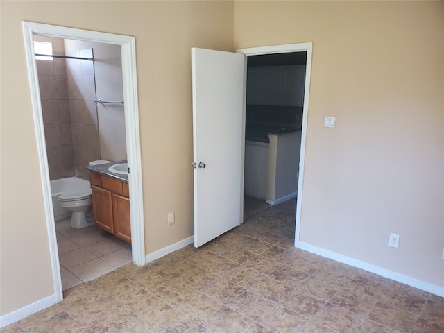 unfurnished bedroom with ensuite bathroom and tile floors