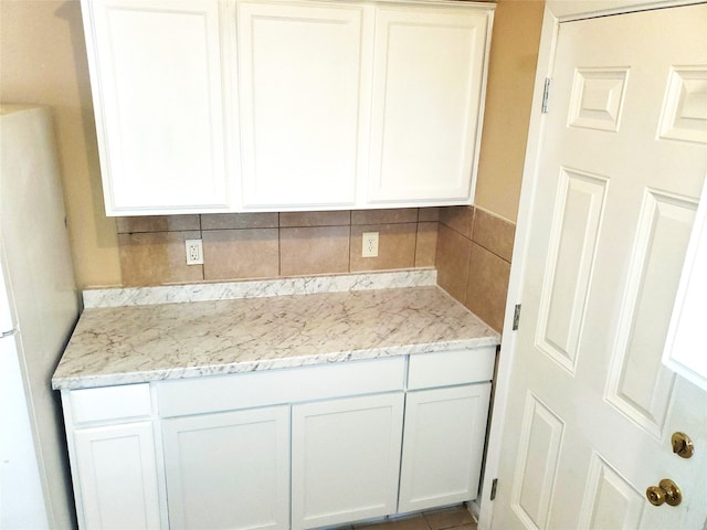 kitchen with backsplash, white cabinetry, and white fridge