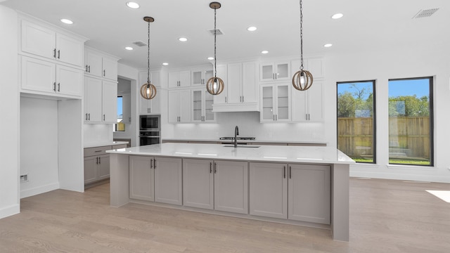 kitchen featuring white cabinetry, sink, hanging light fixtures, a center island with sink, and appliances with stainless steel finishes