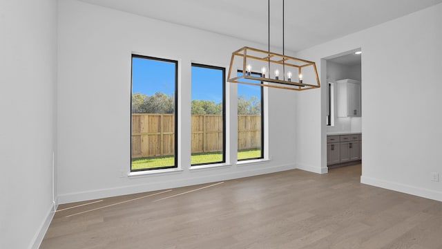 unfurnished dining area featuring light hardwood / wood-style floors and a notable chandelier