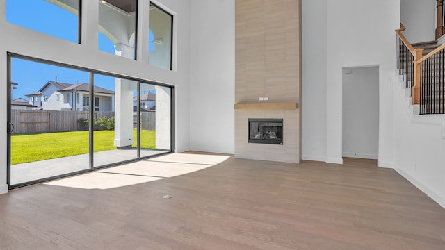 unfurnished living room with hardwood / wood-style floors, a fireplace, and a high ceiling