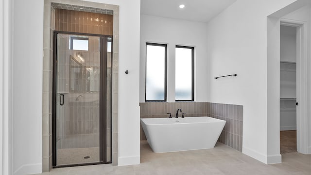 bathroom with tile patterned floors, tile walls, and plus walk in shower