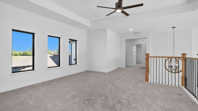 carpeted empty room featuring ceiling fan with notable chandelier