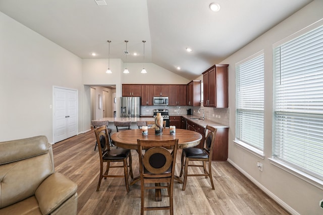 dining space with wood-type flooring, sink, and vaulted ceiling