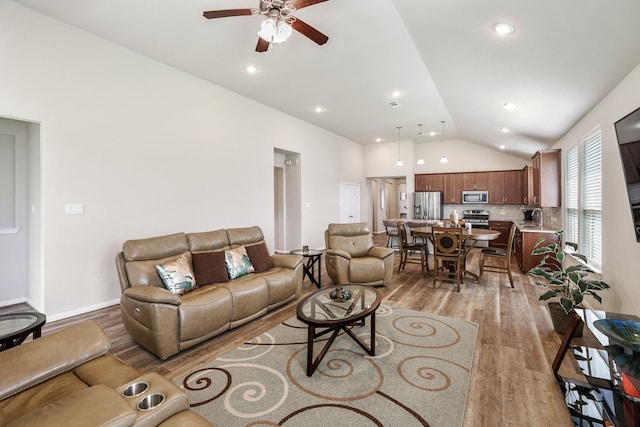 living room with ceiling fan, lofted ceiling, sink, and light hardwood / wood-style flooring