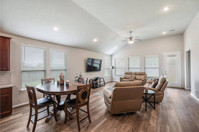 living room featuring a wealth of natural light, ceiling fan, dark wood-type flooring, and vaulted ceiling