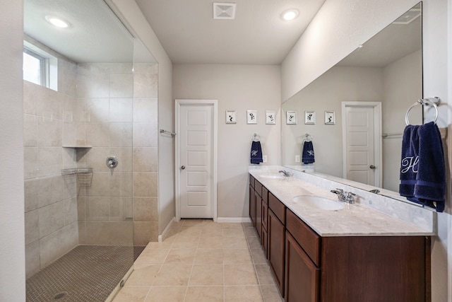 bathroom with a tile shower, vanity, and tile patterned floors