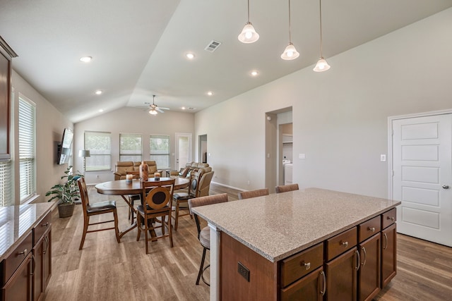 kitchen featuring ceiling fan, a kitchen breakfast bar, light hardwood / wood-style floors, lofted ceiling, and decorative light fixtures