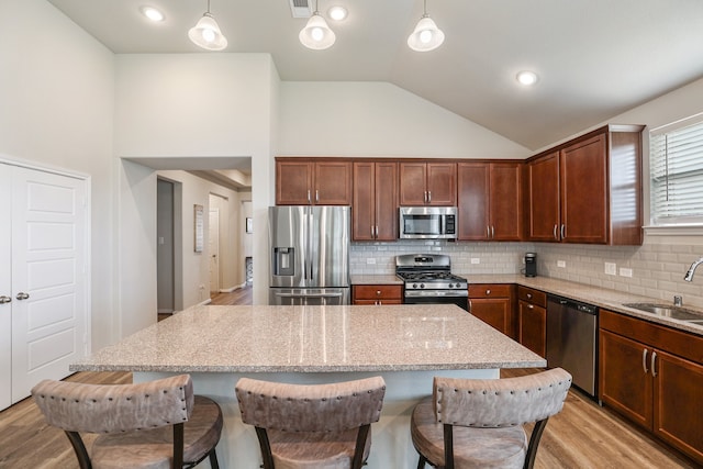 kitchen featuring sink, light hardwood / wood-style flooring, hanging light fixtures, and appliances with stainless steel finishes