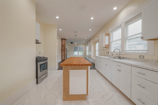 kitchen with white cabinets, gas range, a kitchen island, and a wealth of natural light