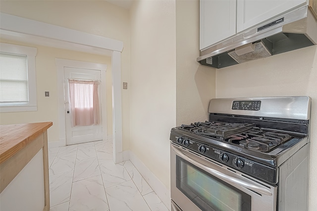 kitchen featuring butcher block countertops, stainless steel gas range, and white cabinets