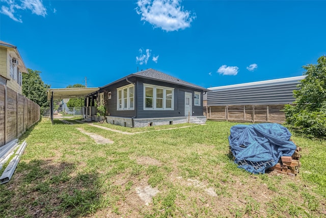 back of house featuring a lawn and a carport