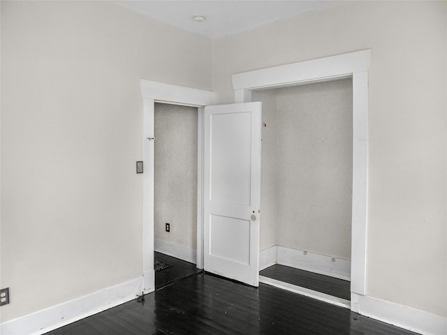 unfurnished bedroom with dark wood-type flooring and a closet