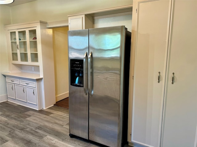 kitchen with hardwood / wood-style floors, stainless steel fridge, and white cabinets