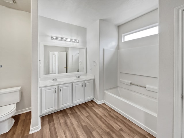 full bathroom with double sink vanity, hardwood / wood-style flooring, shower / bath combination, and toilet