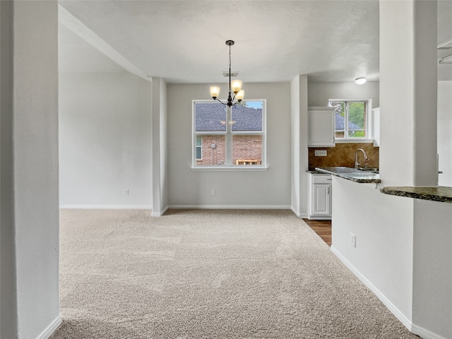 unfurnished dining area with a notable chandelier, sink, and carpet