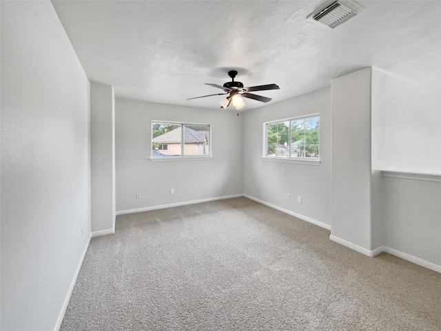 carpeted spare room featuring ceiling fan and a textured ceiling