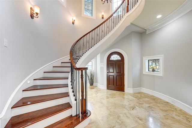 tiled foyer featuring a healthy amount of sunlight, a towering ceiling, and ornamental molding