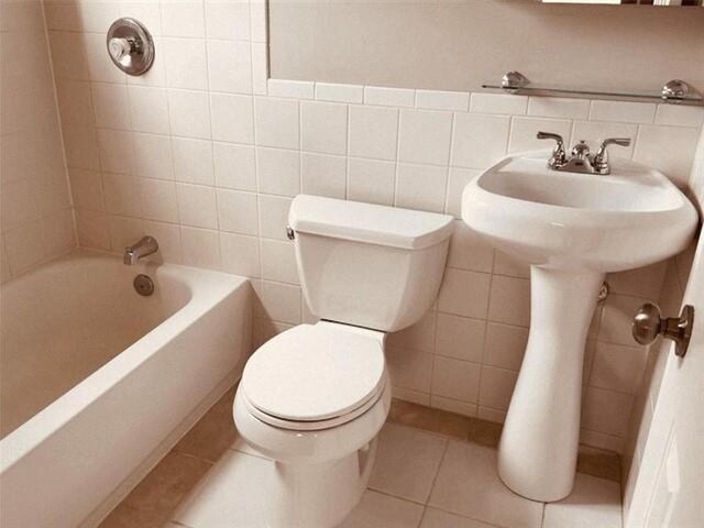 bathroom with tile walls, toilet, tile patterned floors, backsplash, and tiled shower / bath combo