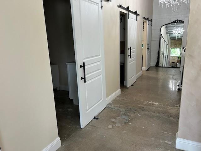 corridor featuring a barn door and concrete flooring