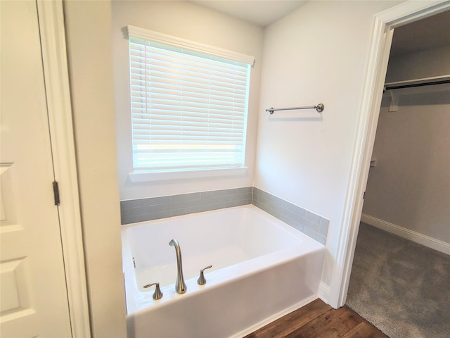 bathroom with wood-type flooring, a wealth of natural light, and a bathing tub