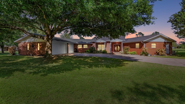 ranch-style house with a garage and a lawn