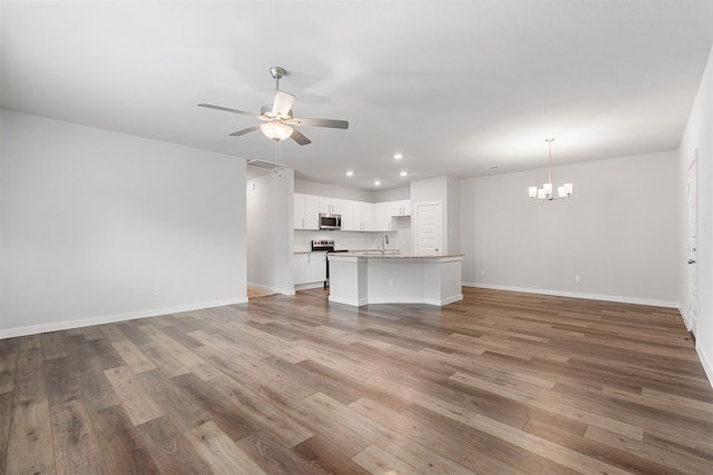 unfurnished living room with sink, wood-type flooring, and ceiling fan with notable chandelier