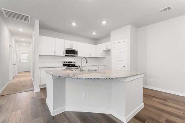 kitchen with white cabinetry, light stone countertops, dark hardwood / wood-style flooring, an island with sink, and stainless steel appliances