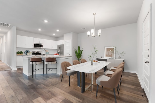 dining area featuring sink, an inviting chandelier, and dark hardwood / wood-style flooring