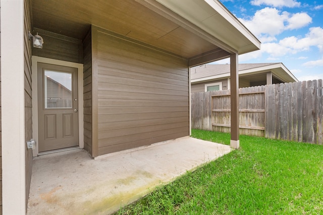 view of exterior entry with a patio area and a yard