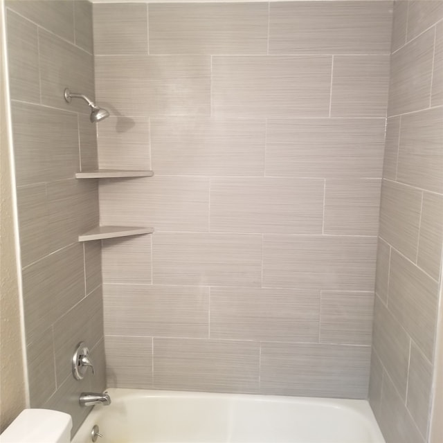 bathroom featuring toilet and tiled shower / bath combo