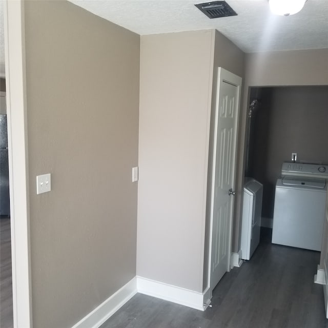 hallway with washer and clothes dryer, a textured ceiling, and dark wood-type flooring