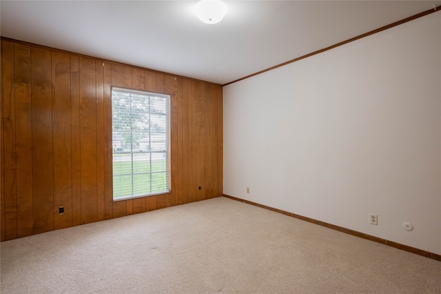 carpeted spare room with wood walls and crown molding