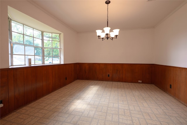 empty room featuring a notable chandelier, wooden walls, and ornamental molding