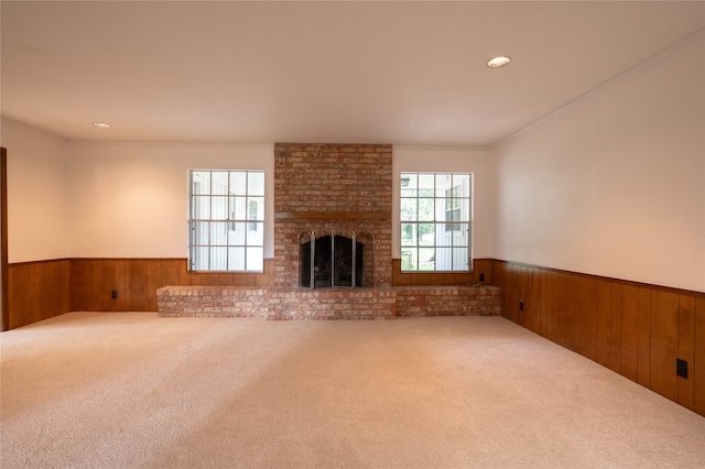 unfurnished living room featuring a brick fireplace, carpet flooring, and wooden walls