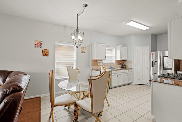 kitchen with tasteful backsplash, decorative light fixtures, light tile floors, white cabinetry, and a chandelier