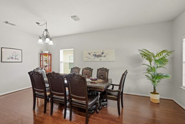 dining area with an inviting chandelier and dark hardwood / wood-style flooring