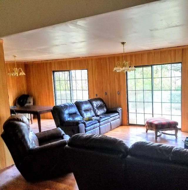 living room with an inviting chandelier, wood walls, and hardwood / wood-style flooring