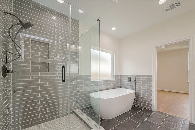 bathroom with tile walls, independent shower and bath, and wood-type flooring