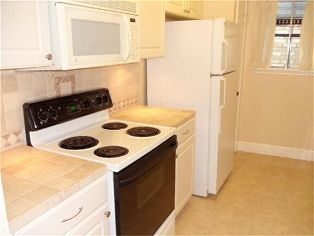 kitchen featuring backsplash, tile counters, white cabinets, and white appliances