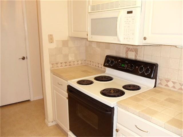 kitchen featuring tasteful backsplash, light tile flooring, white appliances, and white cabinetry