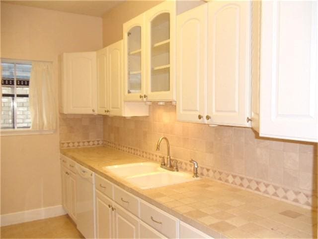 kitchen with sink, white cabinets, backsplash, and dishwasher