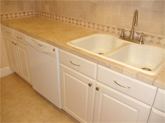 kitchen featuring white cabinetry, sink, dishwasher, and tile counters