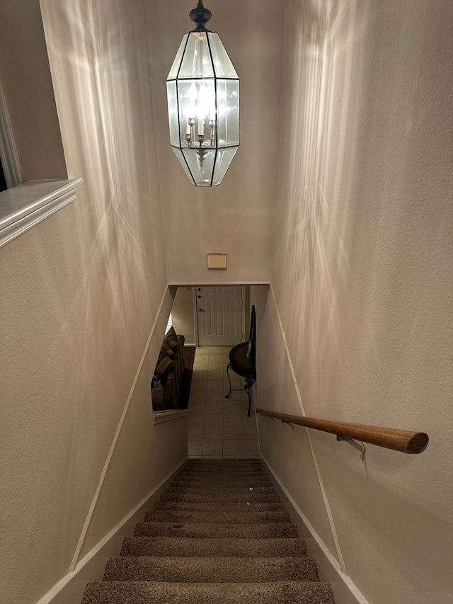 stairway featuring tile floors and a chandelier