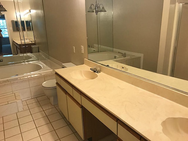 bathroom with tiled bath, double sink vanity, toilet, and tile floors