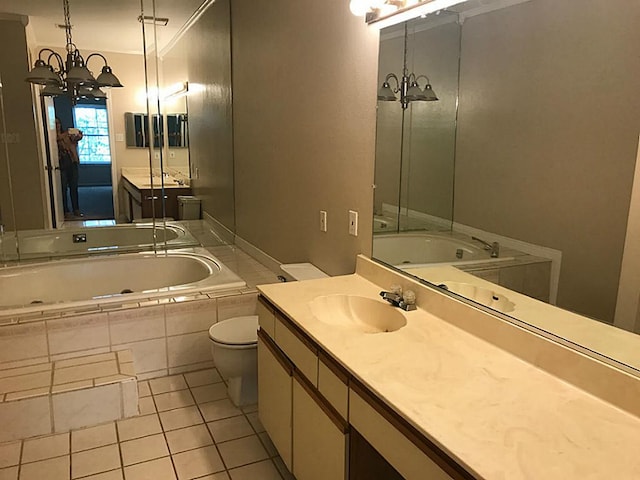 bathroom with tiled tub, toilet, tile flooring, ornamental molding, and vanity