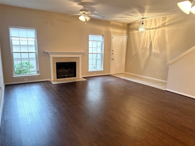 unfurnished living room with dark tile flooring, ceiling fan, and a fireplace