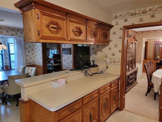 kitchen featuring light carpet, a textured ceiling, and kitchen peninsula